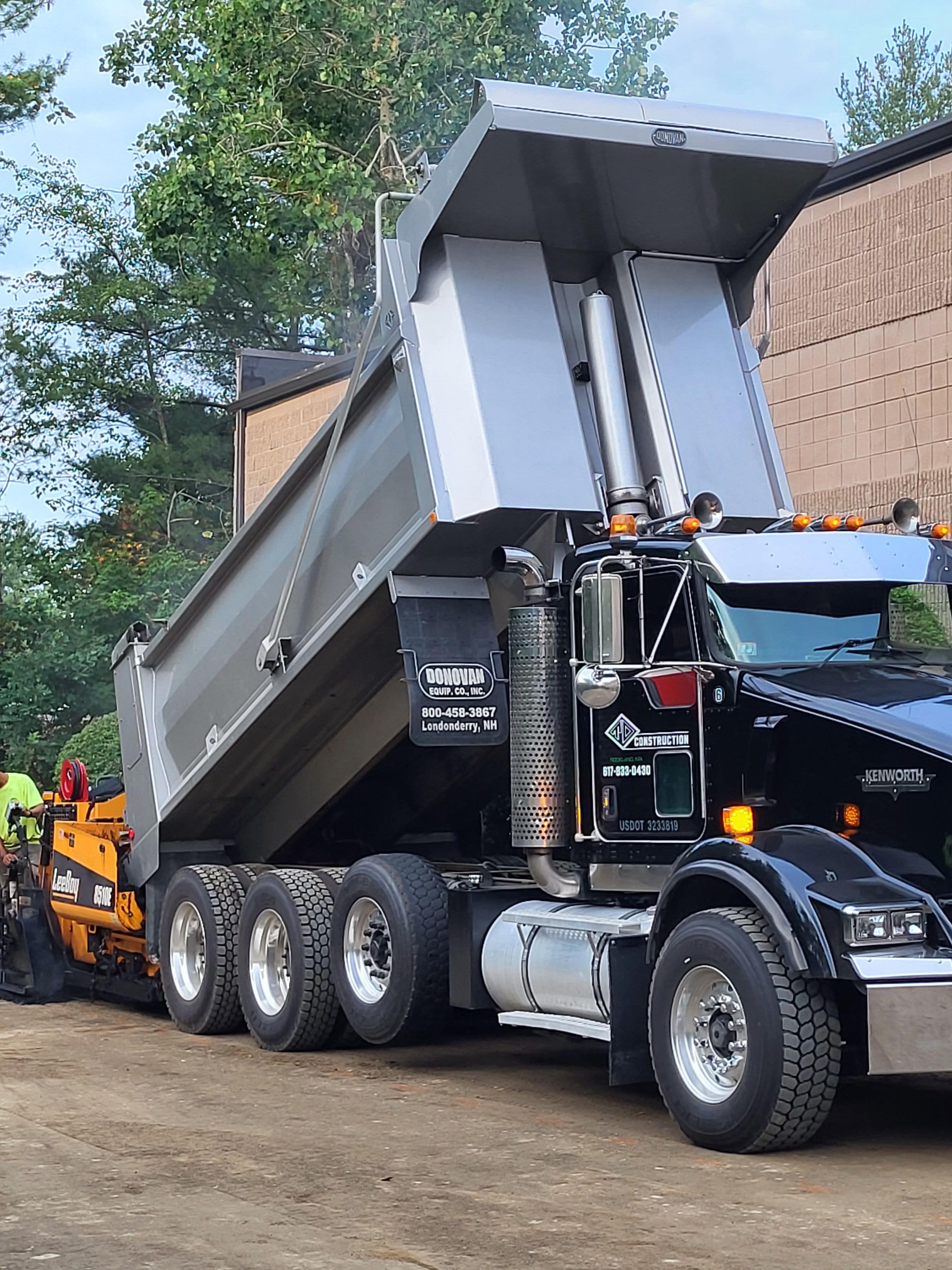 TD Construction has top of the line equipment. Truck shown dumping gravel fora job site. TD Construction logo shown on door.